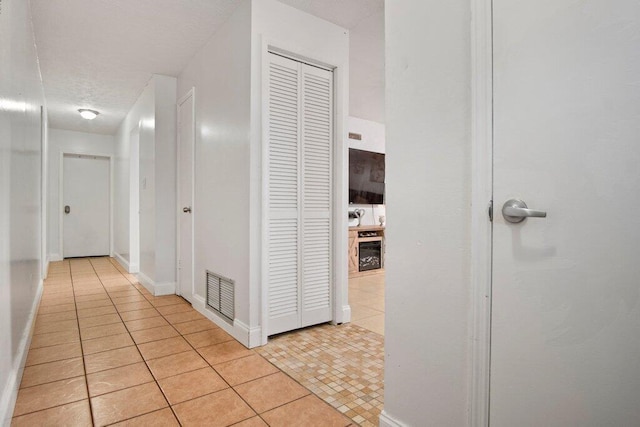 corridor with a textured ceiling and light tile patterned flooring