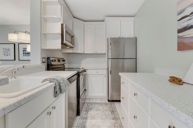 kitchen featuring light stone countertops, appliances with stainless steel finishes, sink, light tile patterned floors, and white cabinets