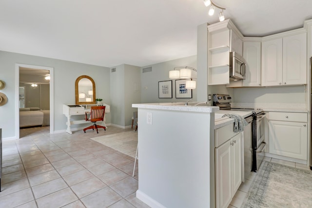 kitchen with kitchen peninsula, white cabinetry, light tile patterned flooring, and stainless steel appliances