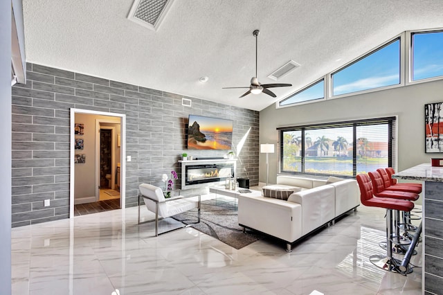 living room featuring a textured ceiling, ceiling fan with notable chandelier, and high vaulted ceiling