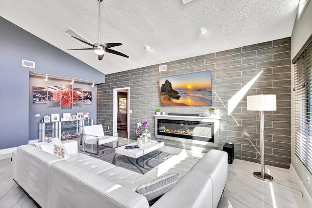 living room with ceiling fan, a fireplace, high vaulted ceiling, and a textured ceiling