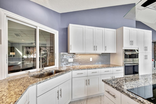 kitchen with white cabinets, sink, a textured ceiling, appliances with stainless steel finishes, and light stone counters