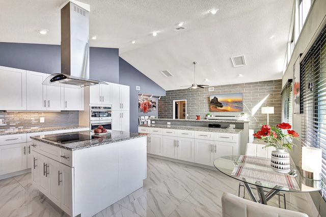 kitchen featuring a textured ceiling, white cabinetry, ceiling fan, and lofted ceiling