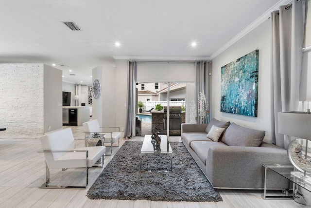 living room with light wood-type flooring and ornamental molding