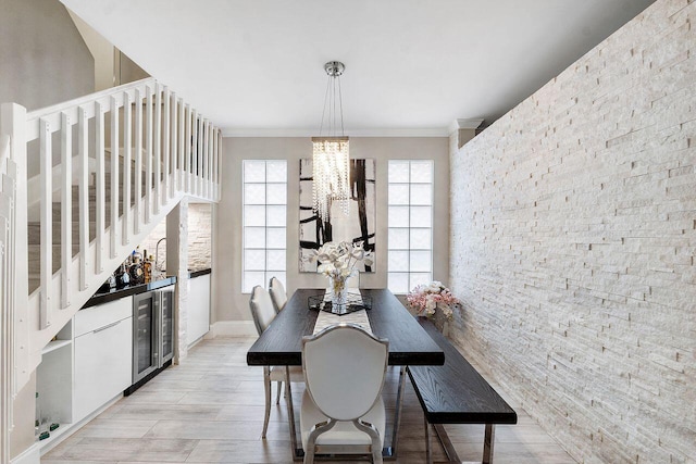 dining space with crown molding, indoor bar, light hardwood / wood-style flooring, a notable chandelier, and wine cooler