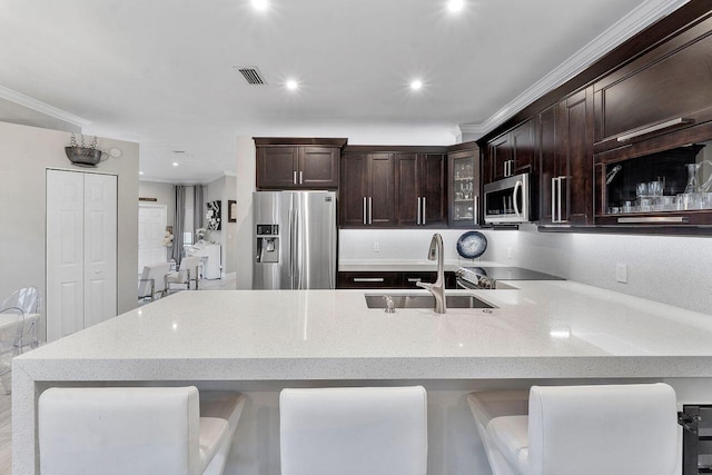 kitchen with light stone countertops, sink, stainless steel appliances, a kitchen bar, and ornamental molding