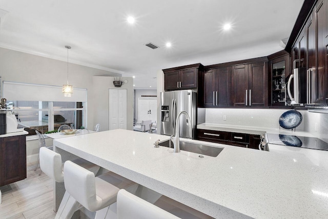 kitchen with light hardwood / wood-style floors, ornamental molding, pendant lighting, and appliances with stainless steel finishes