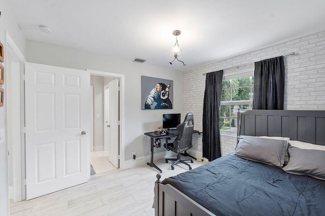 bedroom featuring light hardwood / wood-style flooring and brick wall