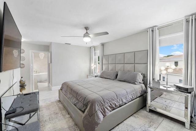 bedroom featuring connected bathroom, light hardwood / wood-style floors, and ceiling fan