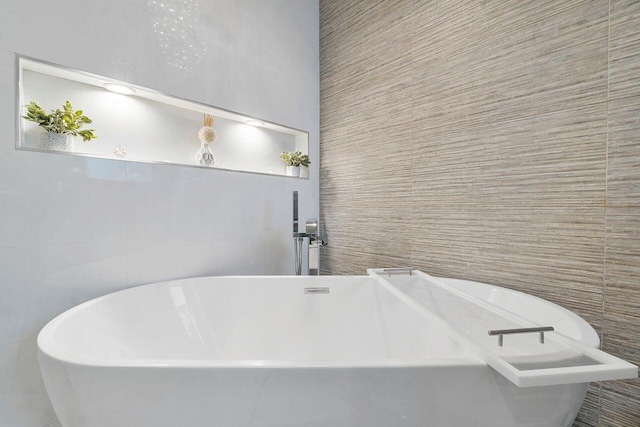 bathroom featuring a bath and tile walls