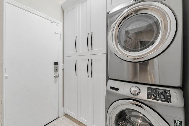 washroom featuring cabinets and stacked washer / dryer