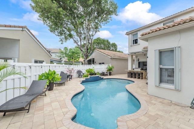 view of swimming pool featuring a patio and an outdoor bar