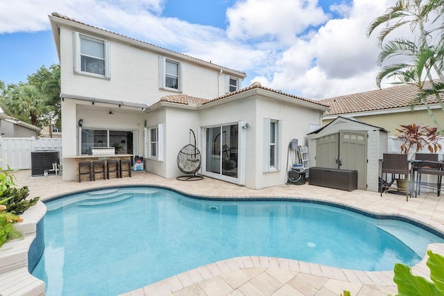 back of property featuring central air condition unit, exterior bar, a shed, and a patio