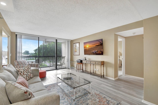 living room featuring a wall of windows, light wood-type flooring, and a textured ceiling