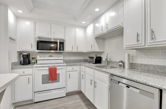 kitchen featuring sink, stainless steel appliances, light hardwood / wood-style floors, a tray ceiling, and white cabinets