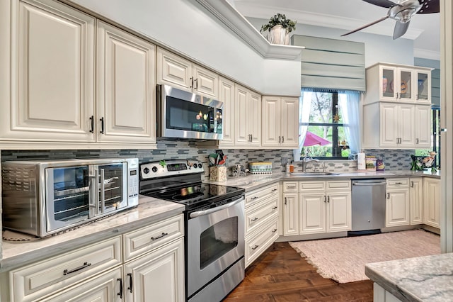 kitchen with sink, light stone countertops, ornamental molding, appliances with stainless steel finishes, and tasteful backsplash