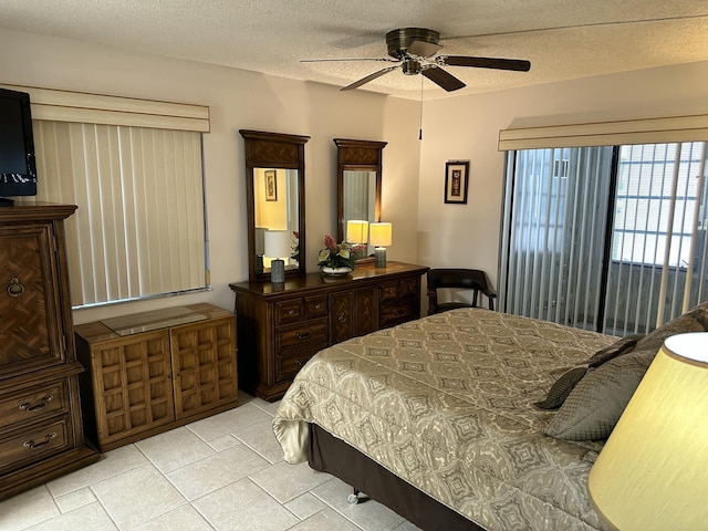 bedroom featuring ceiling fan, light tile patterned floors, and a textured ceiling