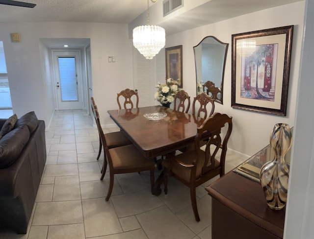 dining room featuring an inviting chandelier, a textured ceiling, and light tile patterned floors