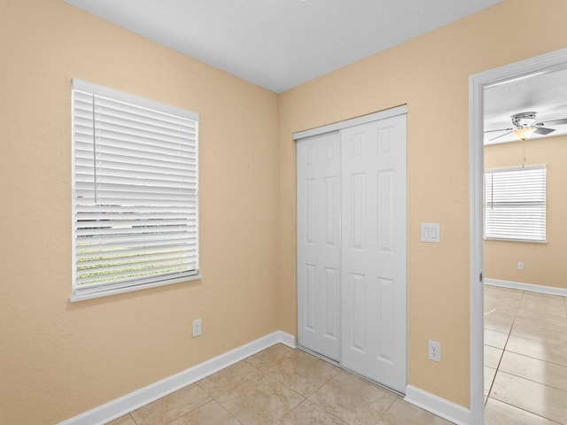 unfurnished bedroom featuring ceiling fan, a closet, light tile patterned floors, and multiple windows