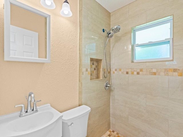 bathroom featuring toilet, sink, and a tile shower