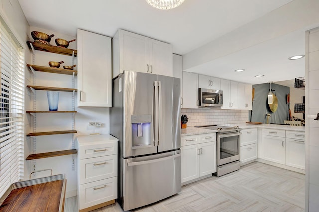 kitchen featuring white cabinets, appliances with stainless steel finishes, light parquet flooring, and decorative backsplash