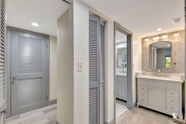 bathroom featuring decorative backsplash, wood-type flooring, and vanity