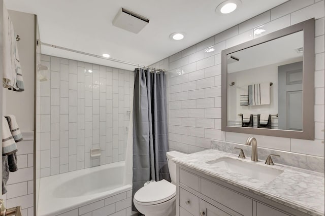 full bathroom with shower / bath combo with shower curtain, vanity, tile walls, and toilet