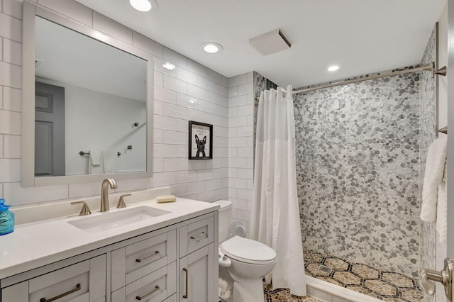 bathroom with walk in shower, vanity, toilet, and tile walls