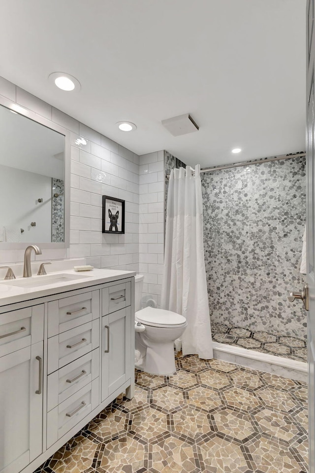 bathroom with vanity, toilet, tile walls, and walk in shower