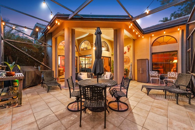 patio terrace at dusk with a lanai and area for grilling