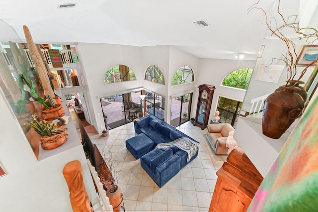 living room featuring light tile patterned floors, plenty of natural light, and a high ceiling