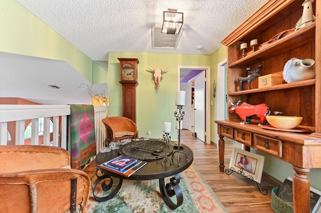 sitting room with light wood-type flooring and a textured ceiling