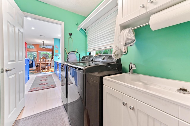 washroom featuring light tile patterned flooring, cabinets, a textured ceiling, and washing machine and clothes dryer