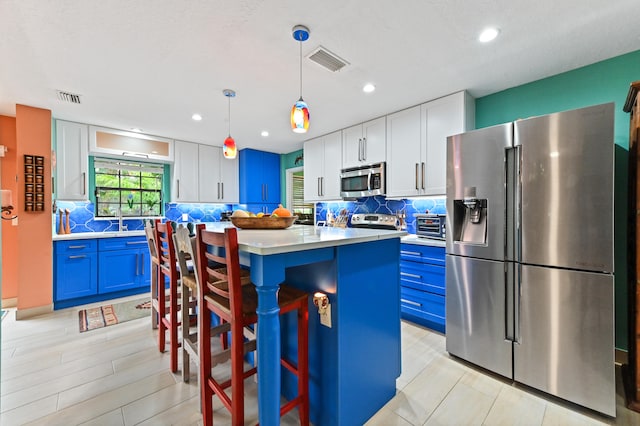 kitchen with white cabinets, hanging light fixtures, blue cabinetry, appliances with stainless steel finishes, and a kitchen island