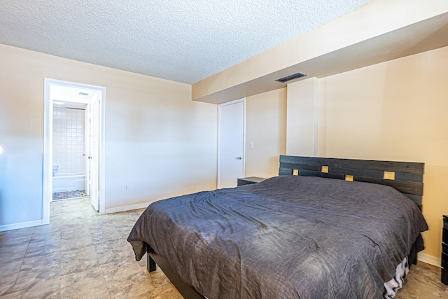 bedroom featuring a textured ceiling and connected bathroom