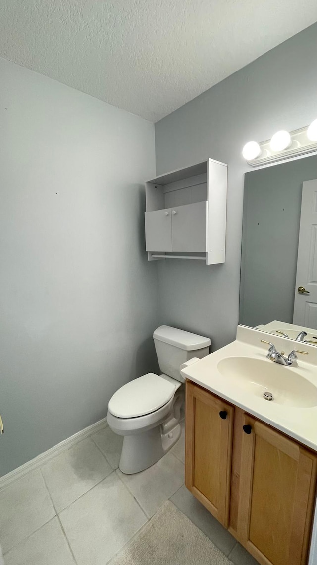 bathroom with tile patterned flooring, vanity, toilet, and a textured ceiling