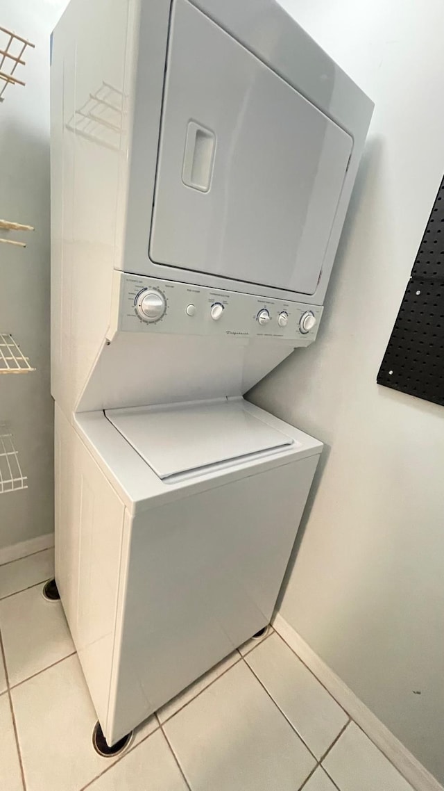 laundry area with light tile patterned floors and stacked washer and dryer