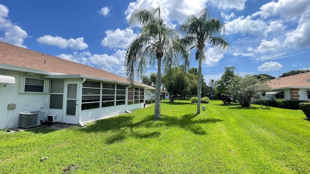 view of yard with a sunroom and central AC unit