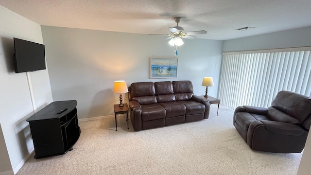 living room featuring carpet flooring, ceiling fan, and a textured ceiling