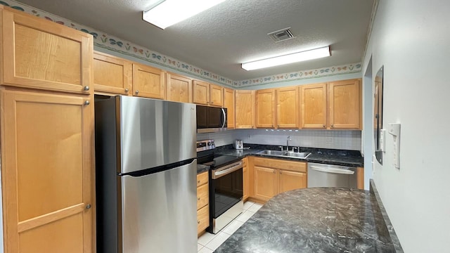 kitchen featuring decorative backsplash, a textured ceiling, stainless steel appliances, sink, and light tile patterned floors