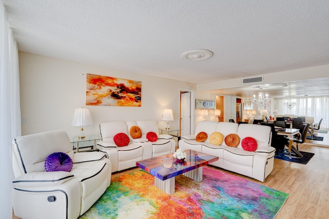 living room with a notable chandelier, a textured ceiling, and light hardwood / wood-style flooring