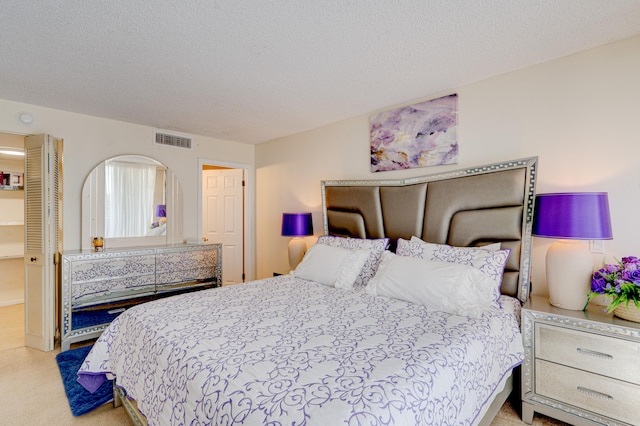 bedroom featuring a textured ceiling and light colored carpet