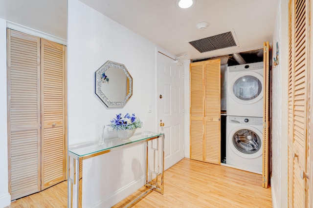 laundry room with stacked washer / drying machine and light wood-type flooring