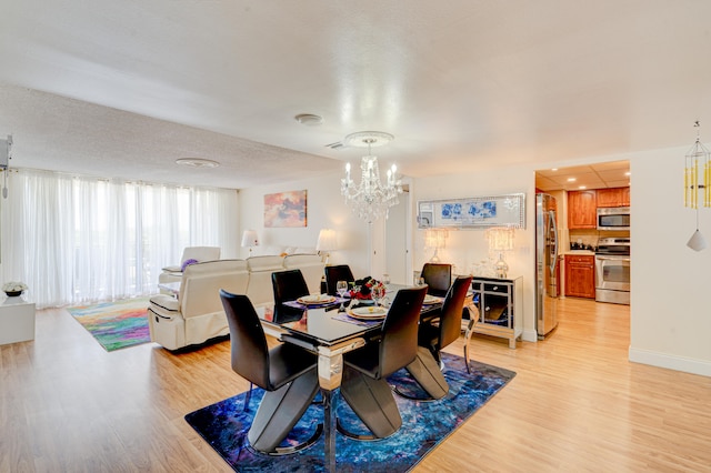 dining area with a chandelier, a textured ceiling, and light hardwood / wood-style flooring