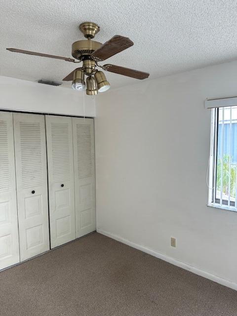 unfurnished bedroom featuring carpet, ceiling fan, a textured ceiling, and a closet