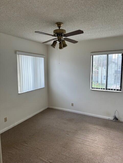 spare room with ceiling fan, carpet, and a textured ceiling