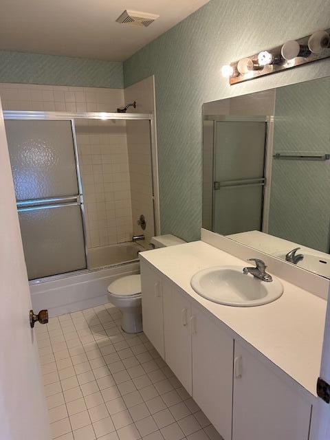 full bathroom featuring tile patterned flooring, vanity, enclosed tub / shower combo, and toilet