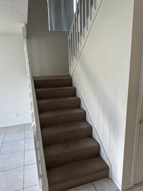 staircase with tile patterned flooring and a textured ceiling