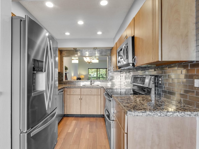 kitchen featuring decorative backsplash, light brown cabinetry, appliances with stainless steel finishes, a sink, and light wood-type flooring