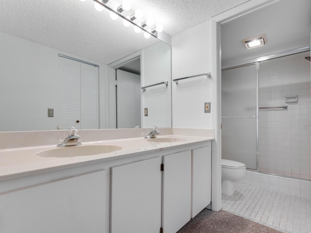 full bathroom with toilet, tile patterned floors, a textured ceiling, a shower stall, and a sink